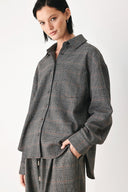 A model wearing a dark gray oversized button-up shirt with a subtle brown and orange windowpane plaid pattern | FREEMARKET