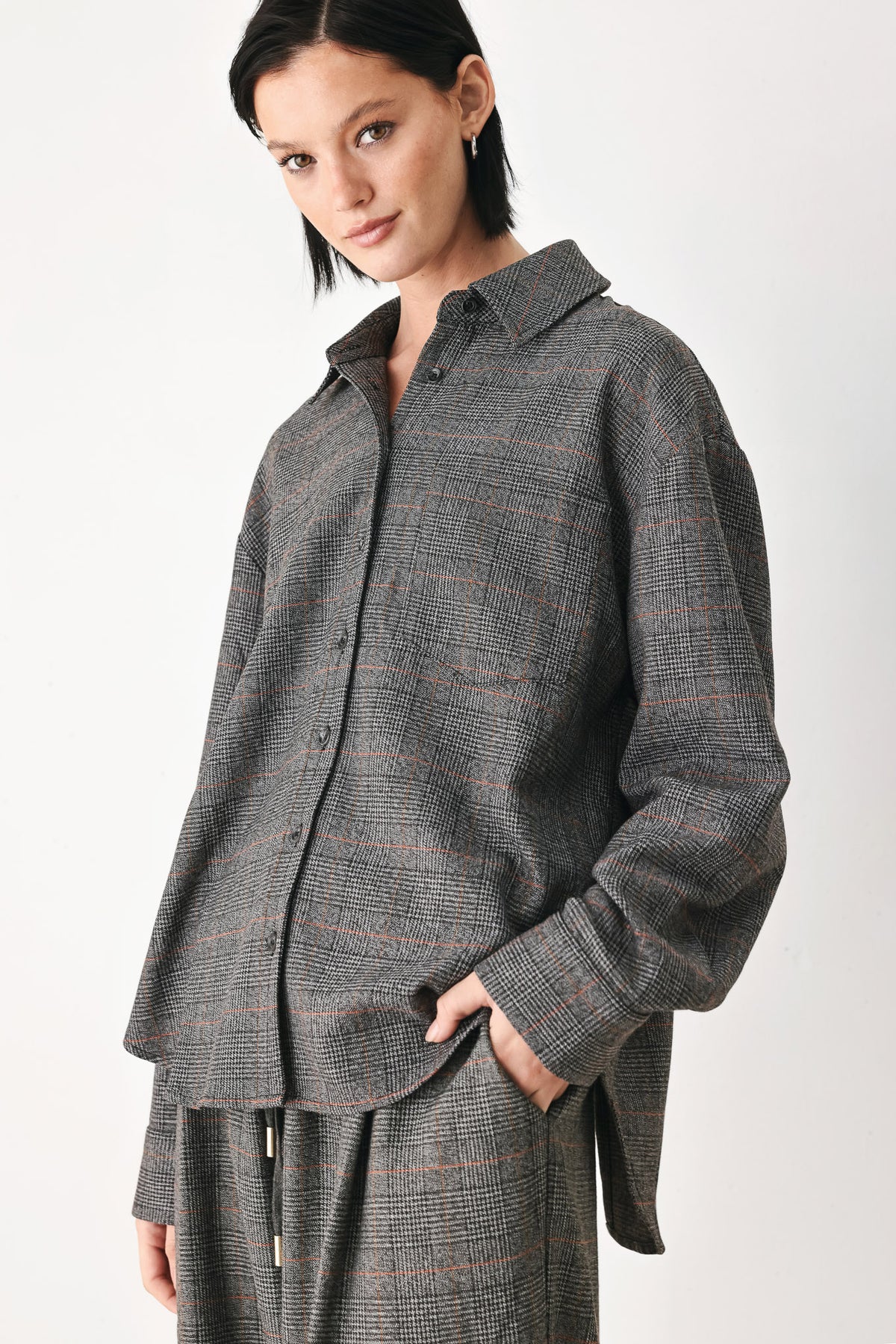 A model wearing a dark gray oversized button-up shirt with a subtle brown and orange windowpane plaid pattern | FREEMARKET