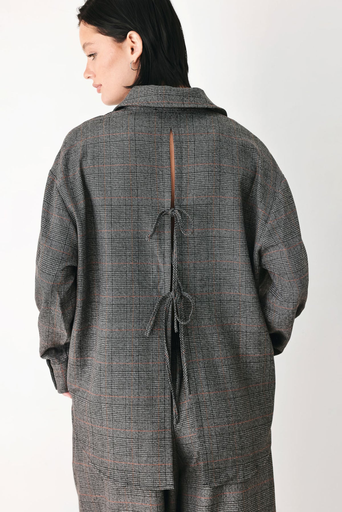 A model wearing a dark gray oversized button-up shirt with a subtle brown and orange windowpane plaid pattern | FREEMARKET