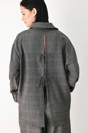 A model wearing a dark gray oversized button-up shirt with a subtle brown and orange windowpane plaid pattern | FREEMARKET