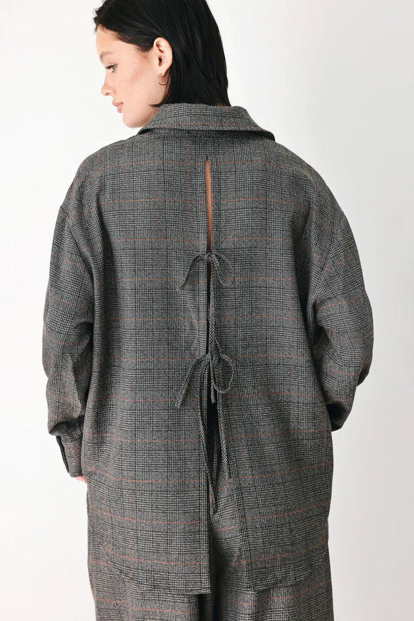 A model wearing a dark gray oversized button-up shirt with a subtle brown and orange windowpane plaid pattern | FREEMARKET
