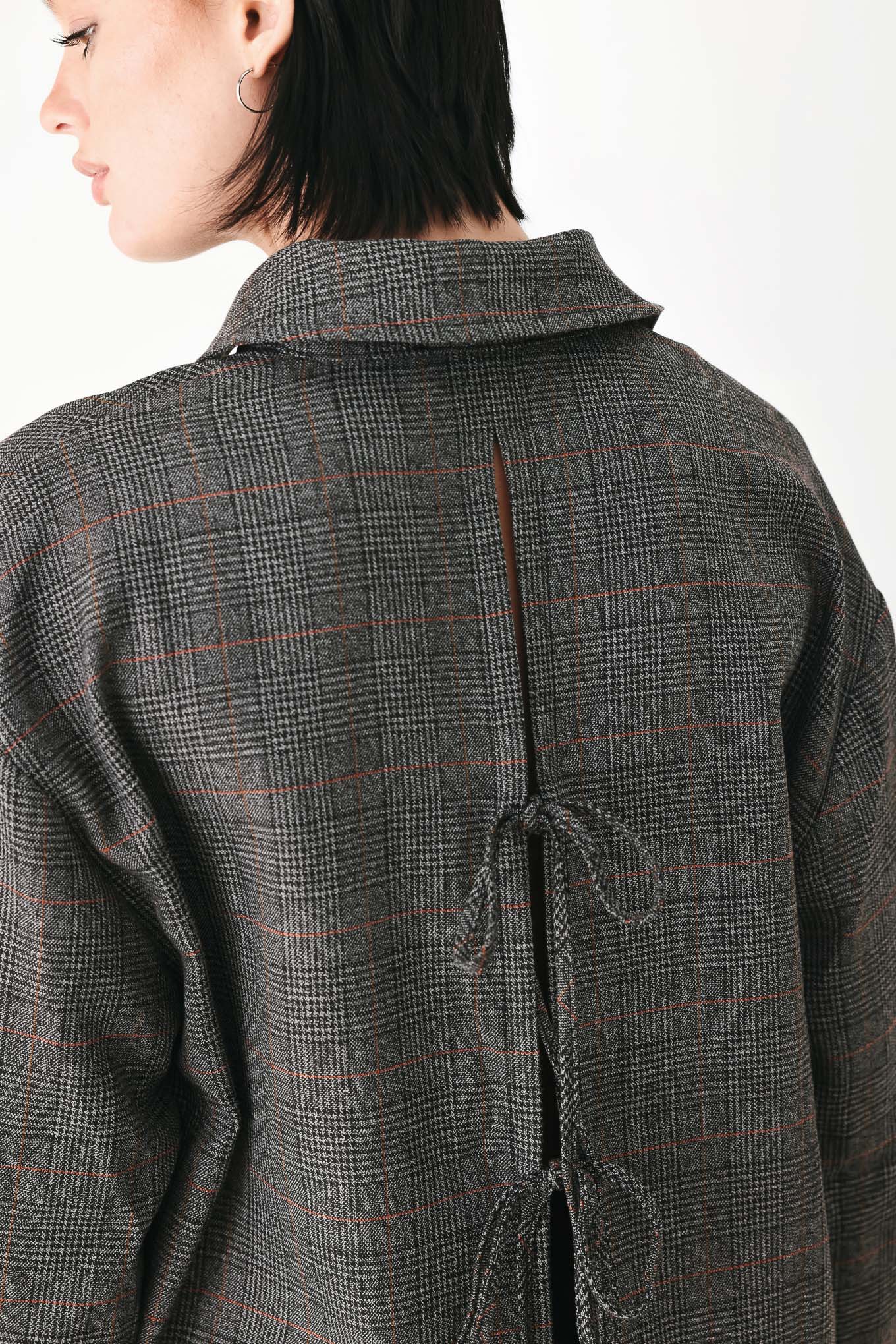 A model wearing a dark gray oversized button-up shirt with a subtle brown and orange windowpane plaid pattern | FREEMARKET
