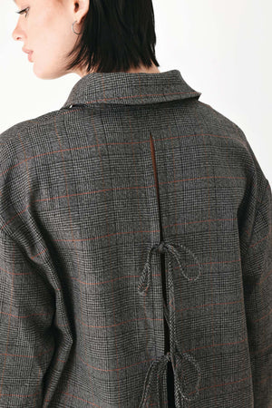 A model wearing a dark gray oversized button-up shirt with a subtle brown and orange windowpane plaid pattern | FREEMARKET
