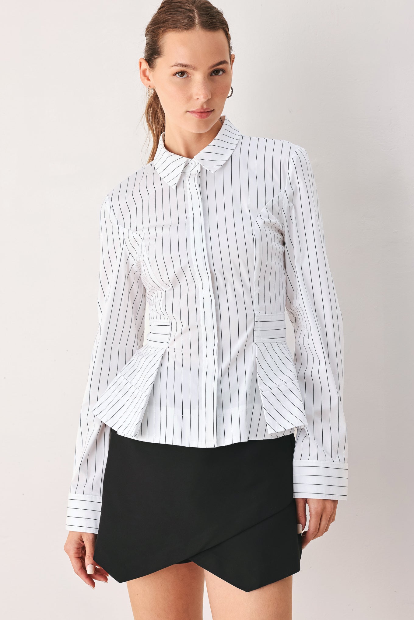 A woman wearing a white long-sleeve button-up shirt with thin vertical black stripes| FREEMARKET