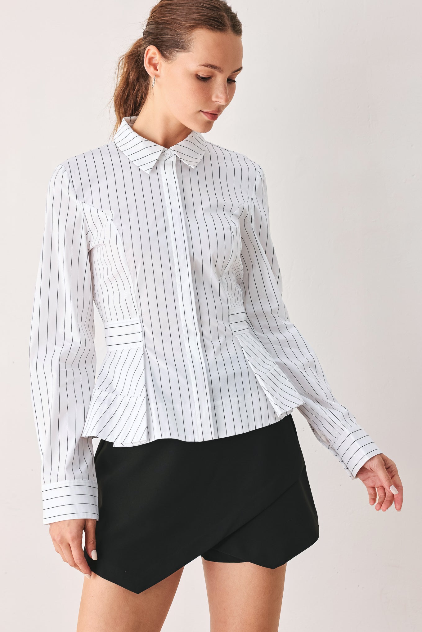 A woman wearing a white long-sleeve button-up shirt with thin vertical black stripes| FREEMARKET