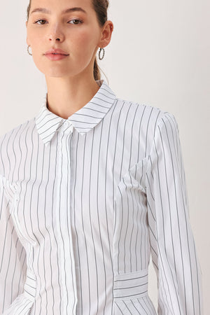 A woman wearing a white long-sleeve button-up shirt with thin vertical black stripes| FREEMARKET