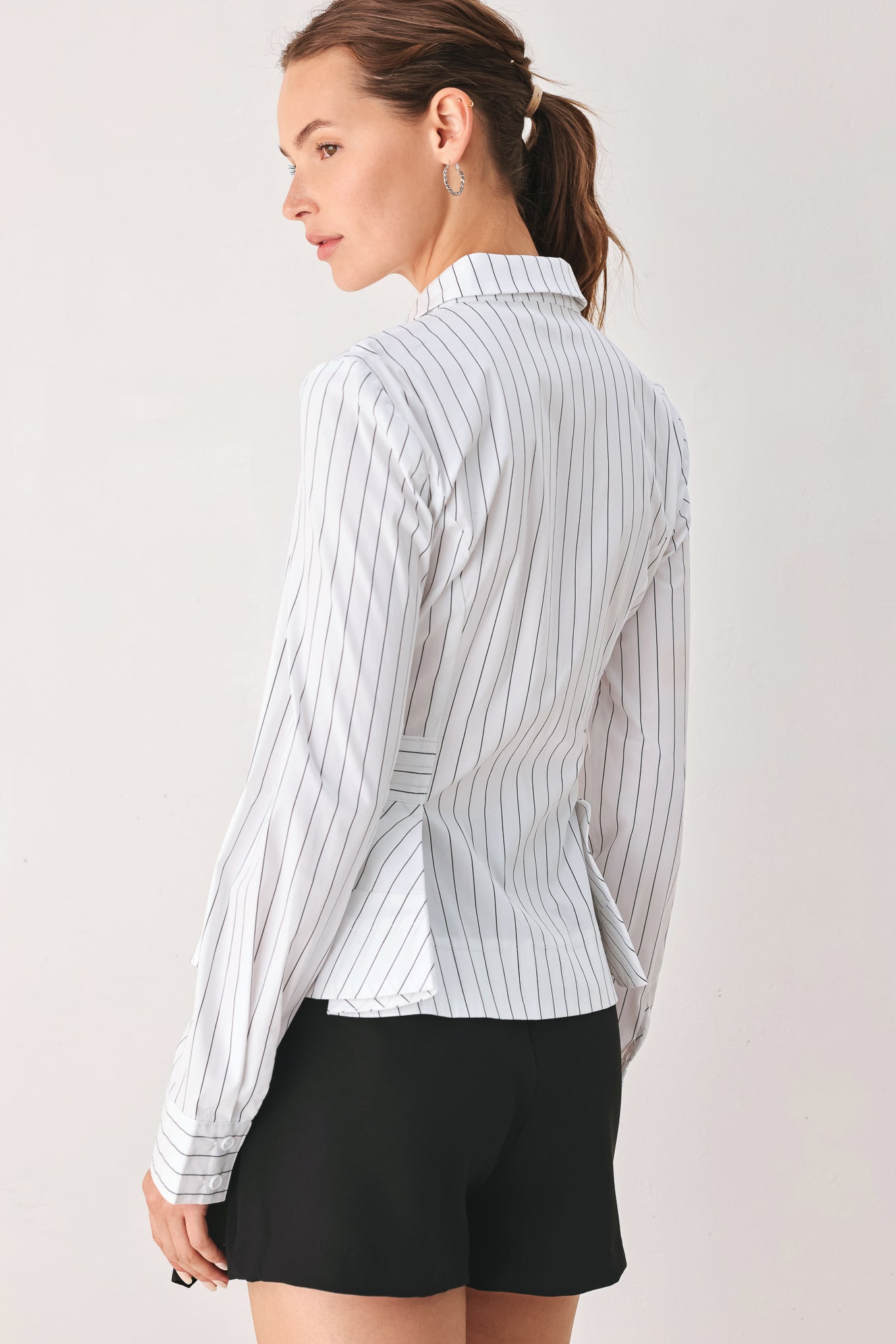 A woman wearing a white long-sleeve button-up shirt with thin vertical black stripes| FREEMARKET
