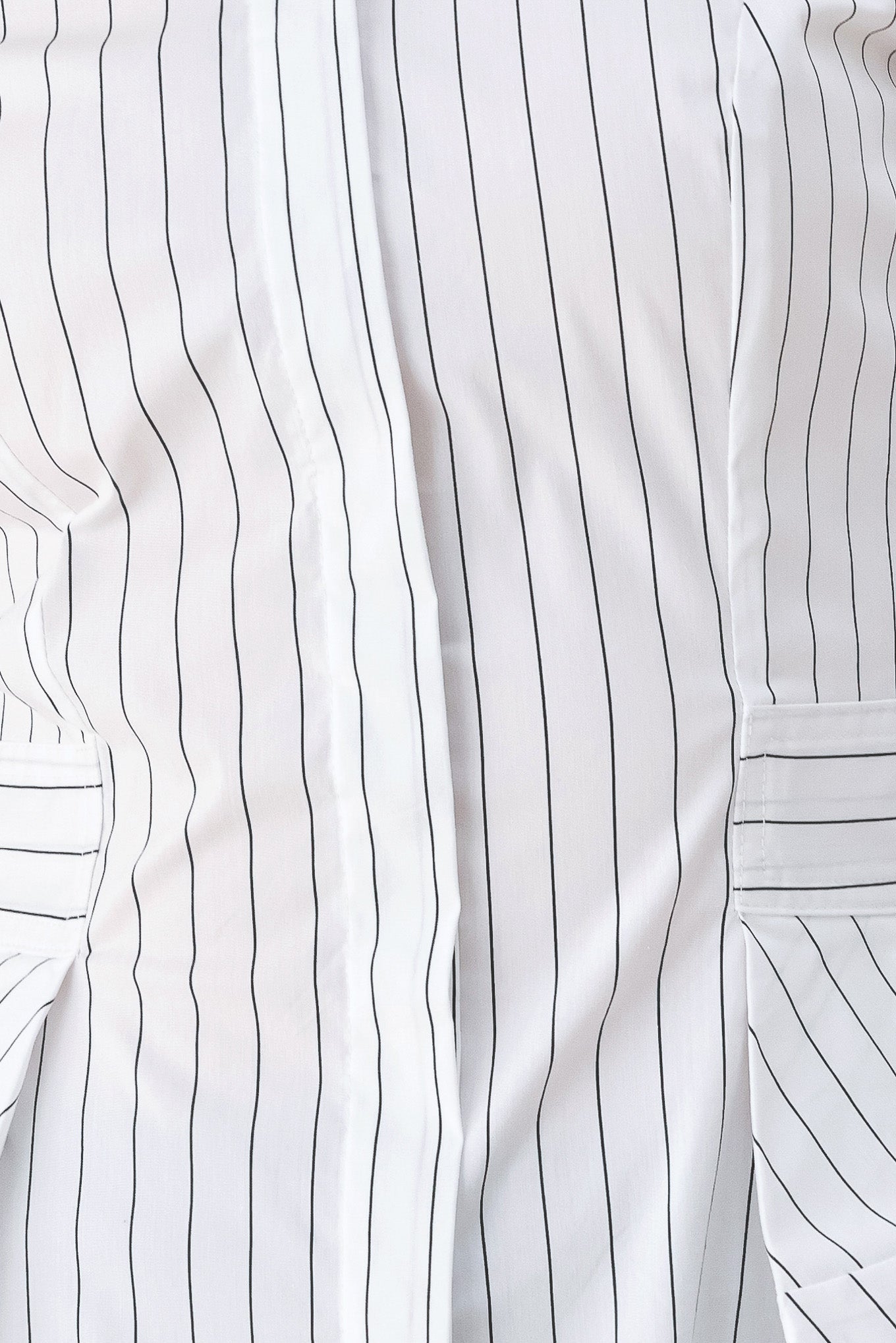 A woman wearing a white long-sleeve button-up shirt with thin vertical black stripes| FREEMARKET