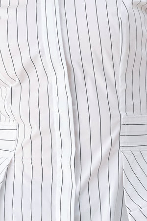 A woman wearing a white long-sleeve button-up shirt with thin vertical black stripes| FREEMARKET