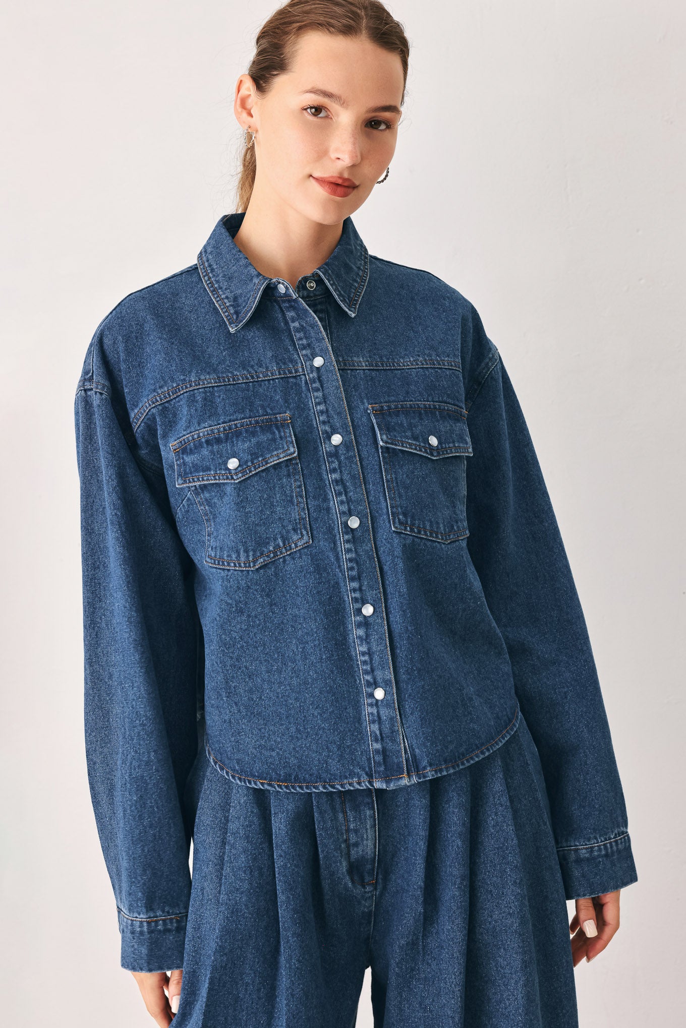 A woman wearing a dark blue denim button-up shirt jacket with two chest pockets | FREEMARKET