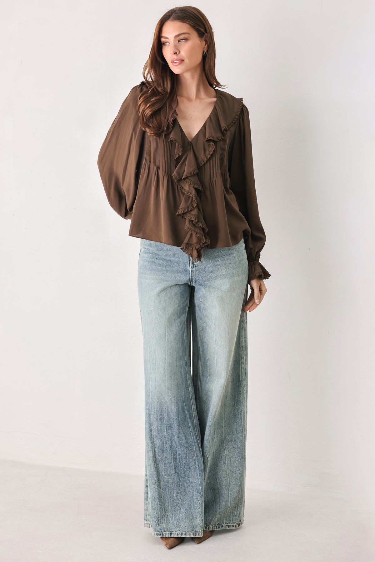 A woman wearing a brown long-sleeve blouse with pleated detailing and layered ruffles on the front | FREEMARKET