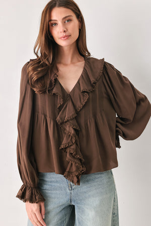 A woman wearing a brown long-sleeve blouse with pleated detailing and layered ruffles on the front | FREEMARKET