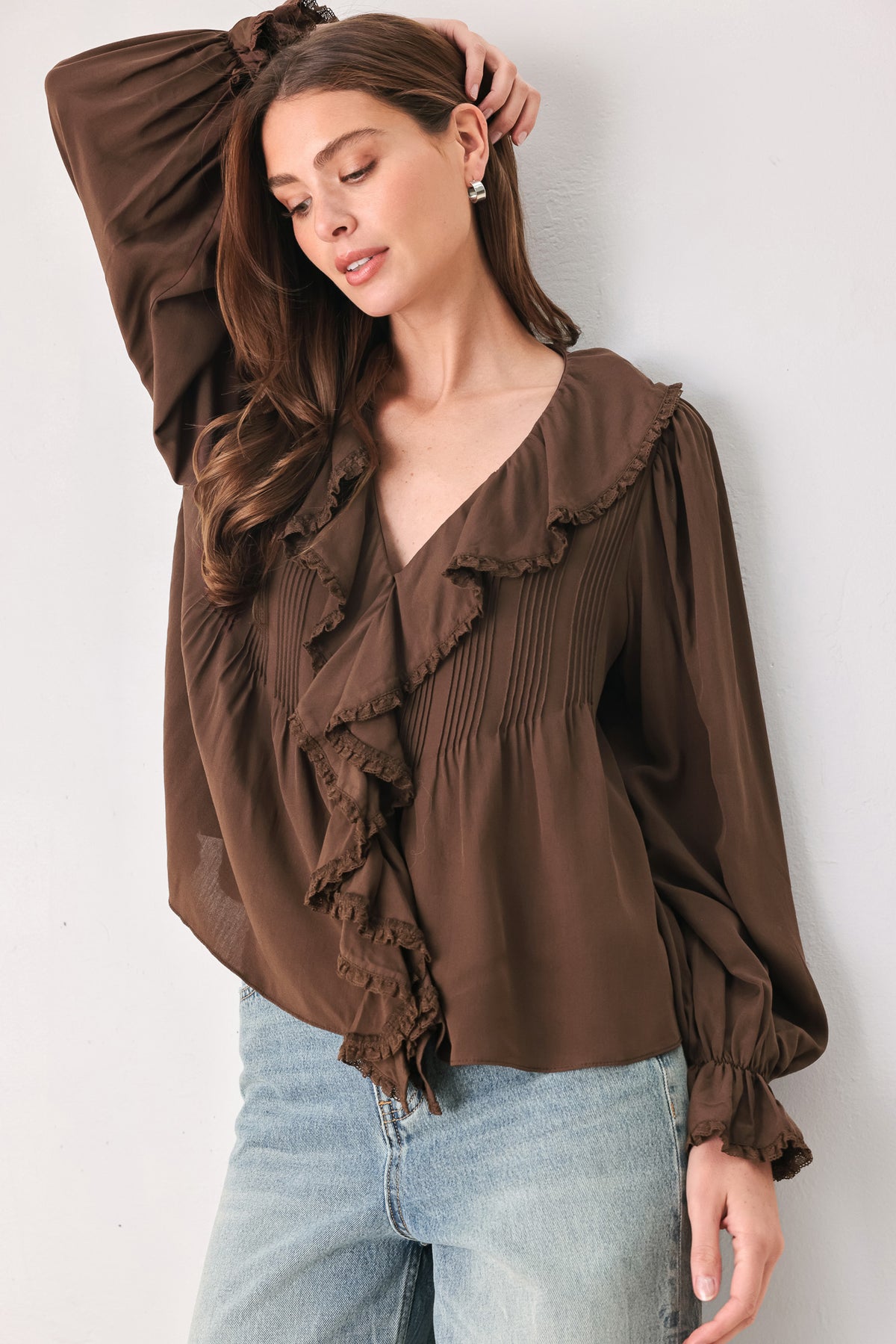 A woman wearing a brown long-sleeve blouse with pleated detailing and layered ruffles on the front | FREEMARKET