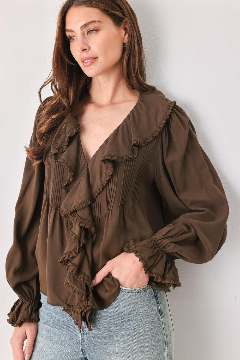 A woman wearing a brown long-sleeve blouse with pleated detailing and layered ruffles on the front | FREEMARKET