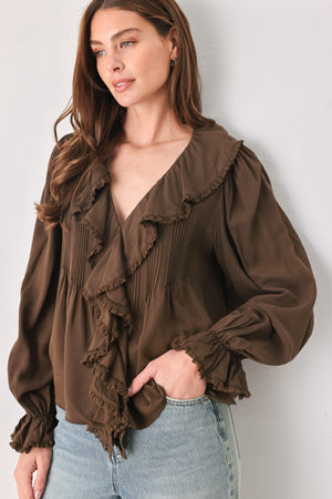 A woman wearing a brown long-sleeve blouse with pleated detailing and layered ruffles on the front | FREEMARKET