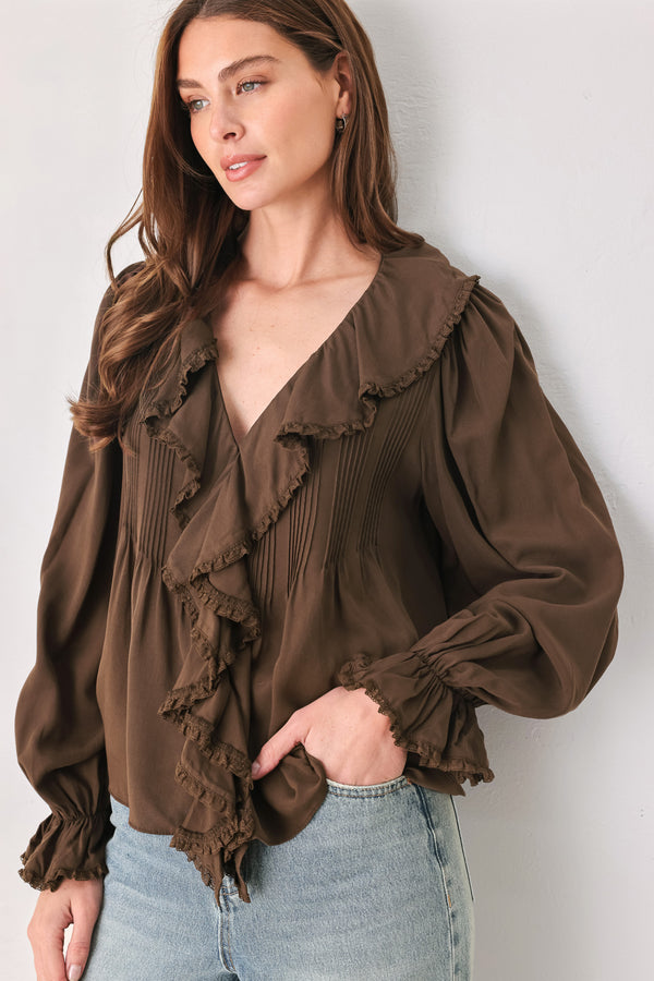 A woman wearing a brown long-sleeve blouse with pleated detailing and layered ruffles on the front | FREEMARKET