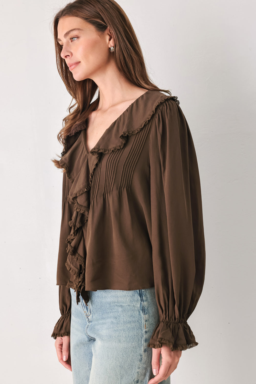 A woman wearing a brown long-sleeve blouse with pleated detailing and layered ruffles on the front | FREEMARKET