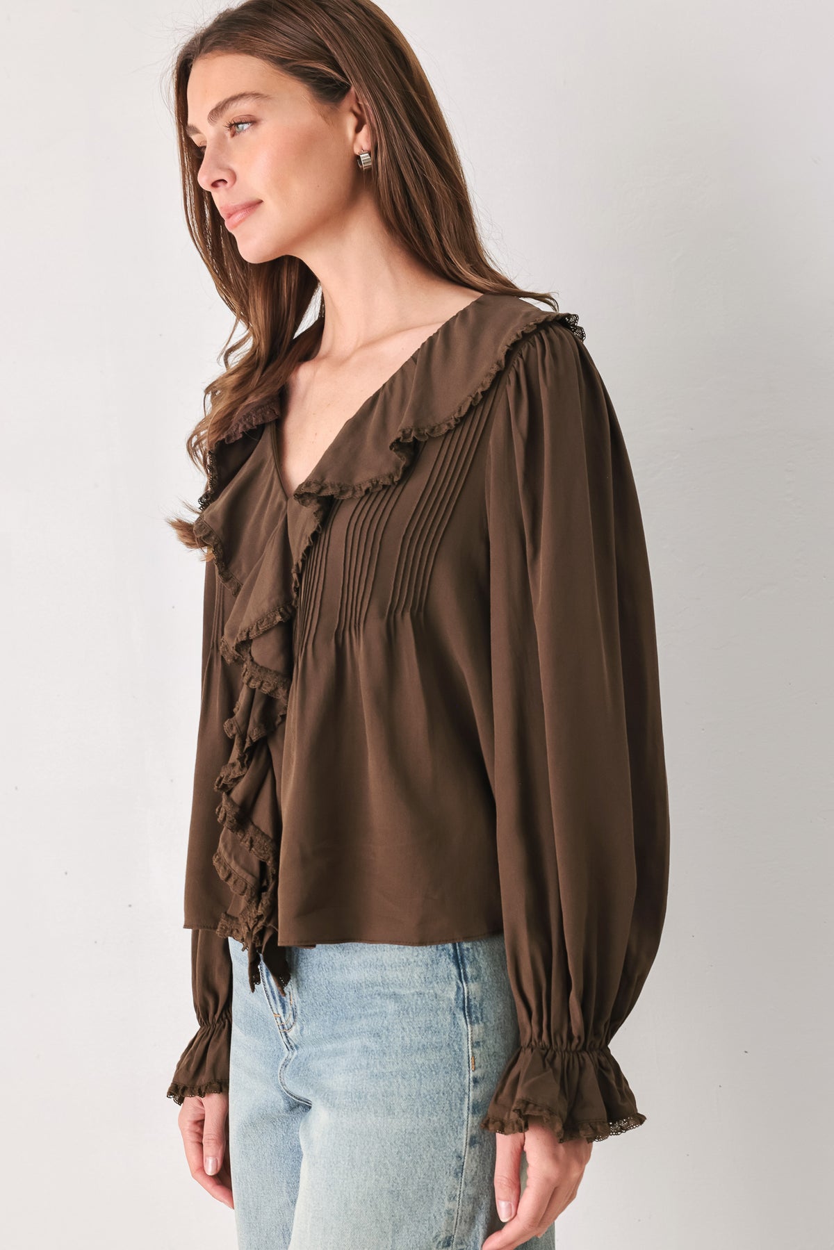 A woman wearing a brown long-sleeve blouse with pleated detailing and layered ruffles on the front | FREEMARKET