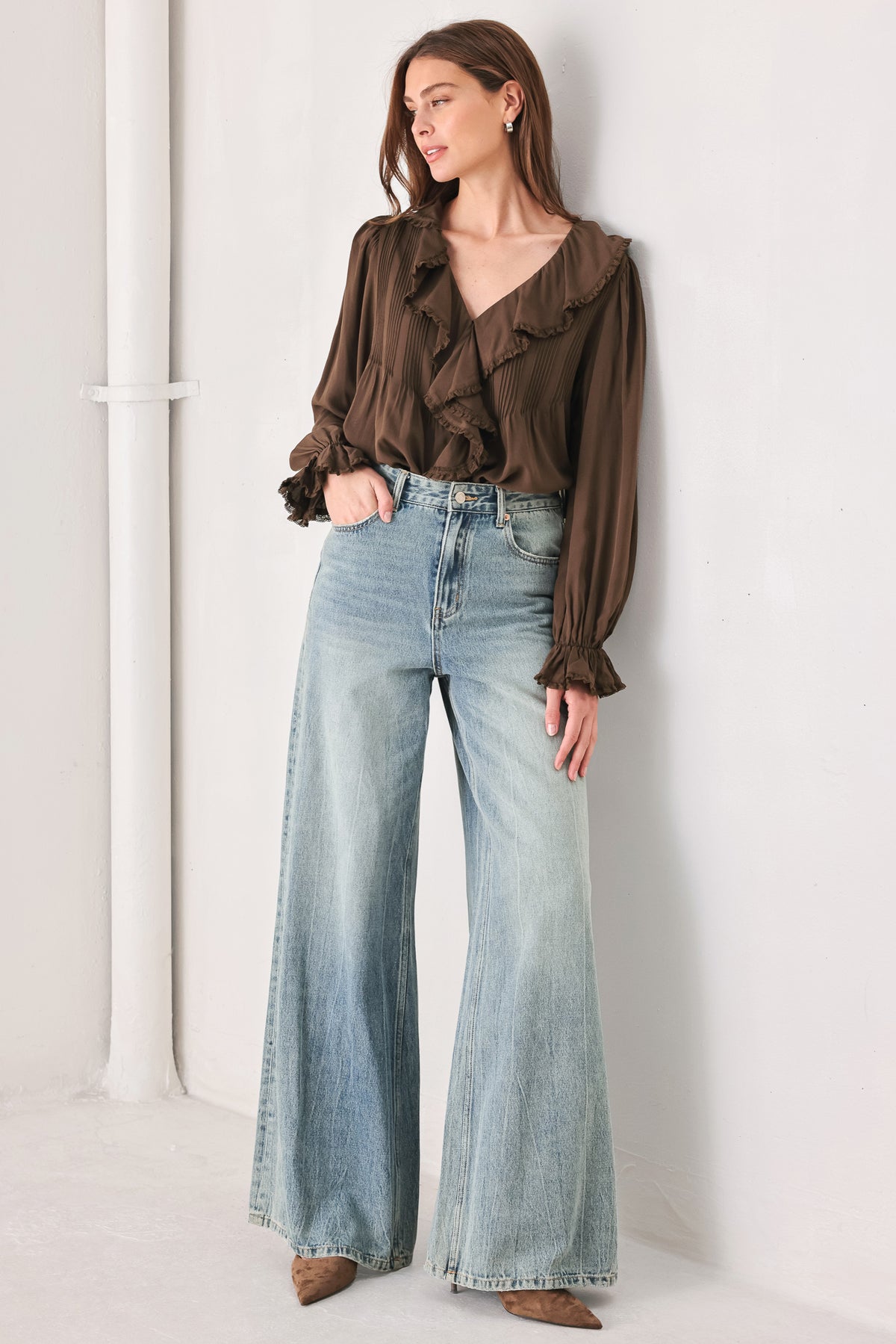 A woman wearing a brown long-sleeve blouse with pleated detailing and layered ruffles on the front | FREEMARKET