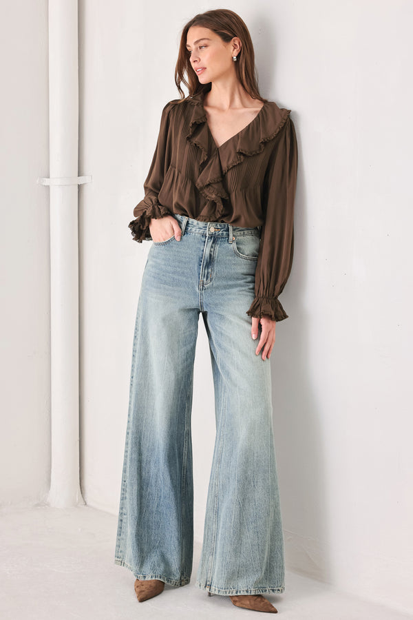 A woman wearing a brown long-sleeve blouse with pleated detailing and layered ruffles on the front | FREEMARKET