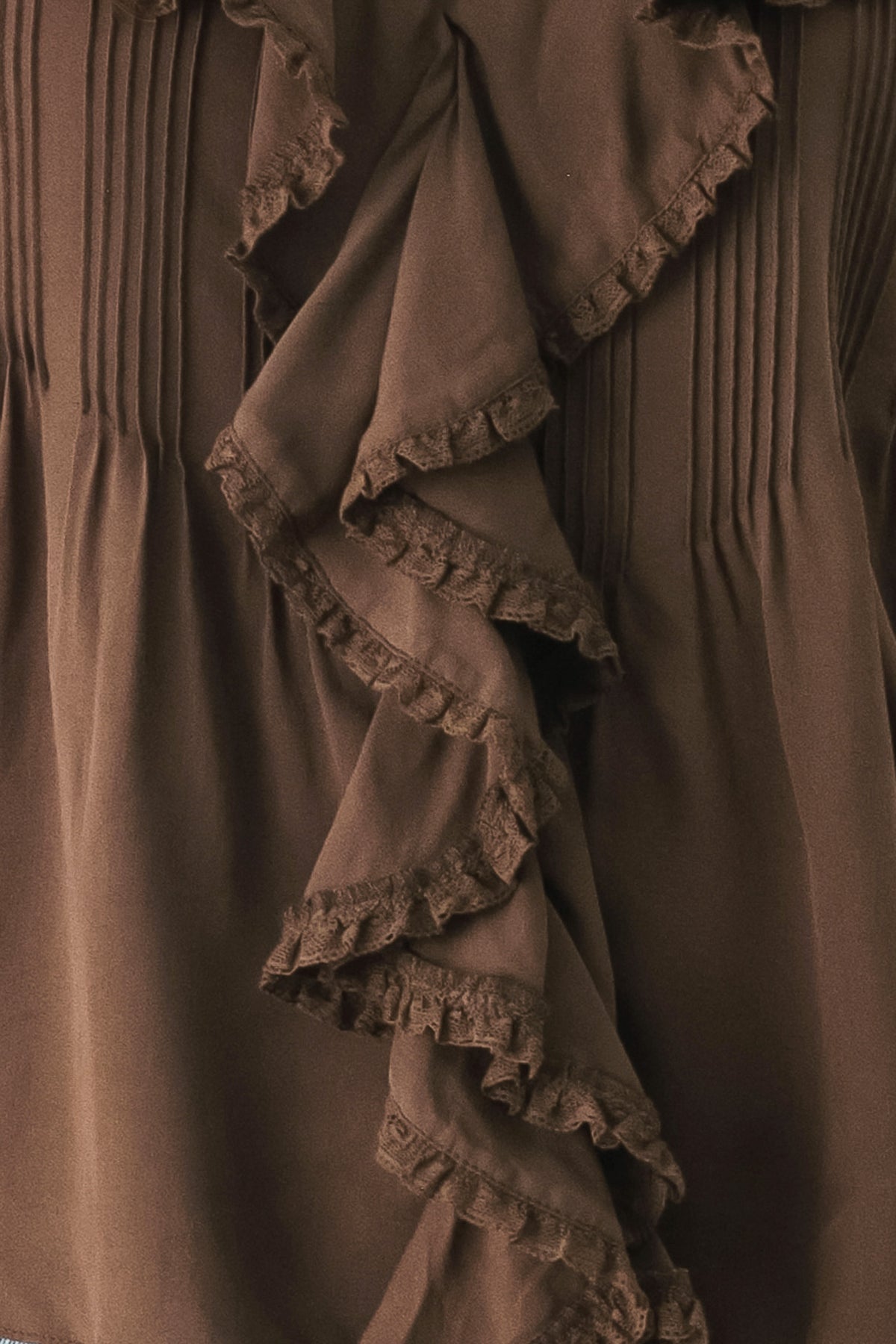 A woman wearing a brown long-sleeve blouse with pleated detailing and layered ruffles on the front | FREEMARKET