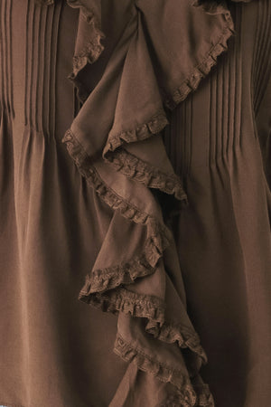 A woman wearing a brown long-sleeve blouse with pleated detailing and layered ruffles on the front | FREEMARKET