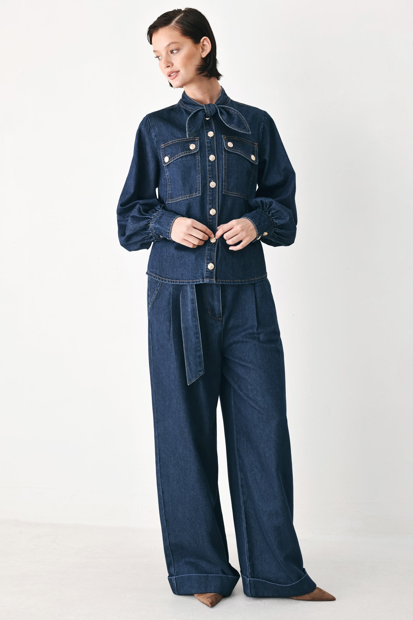 A model wearing a dark blue denim shirt jacket with gold-tone buttons and a bow detail at the collar | FREEMARKET
