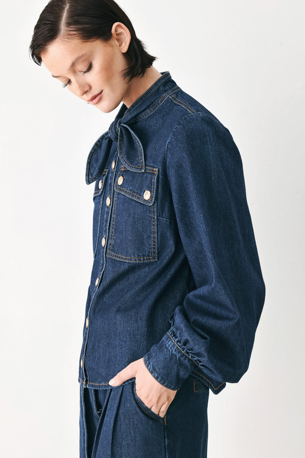 A model wearing a dark blue denim shirt jacket with gold-tone buttons and a bow detail at the collar | FREEMARKET