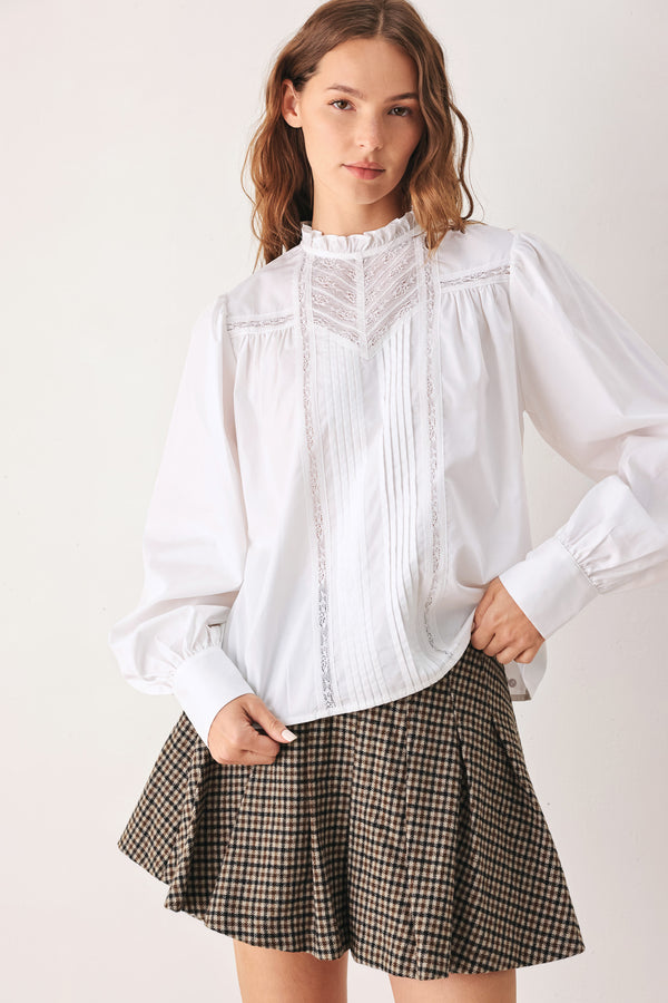 A woman modeling a white long-sleeve blouse with a ruffled high neck, pleated front, and lace detailing | FREEMARKET
