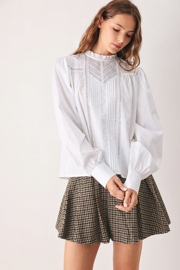 A woman modeling a white long-sleeve blouse with a ruffled high neck, pleated front, and lace detailing | FREEMARKET
