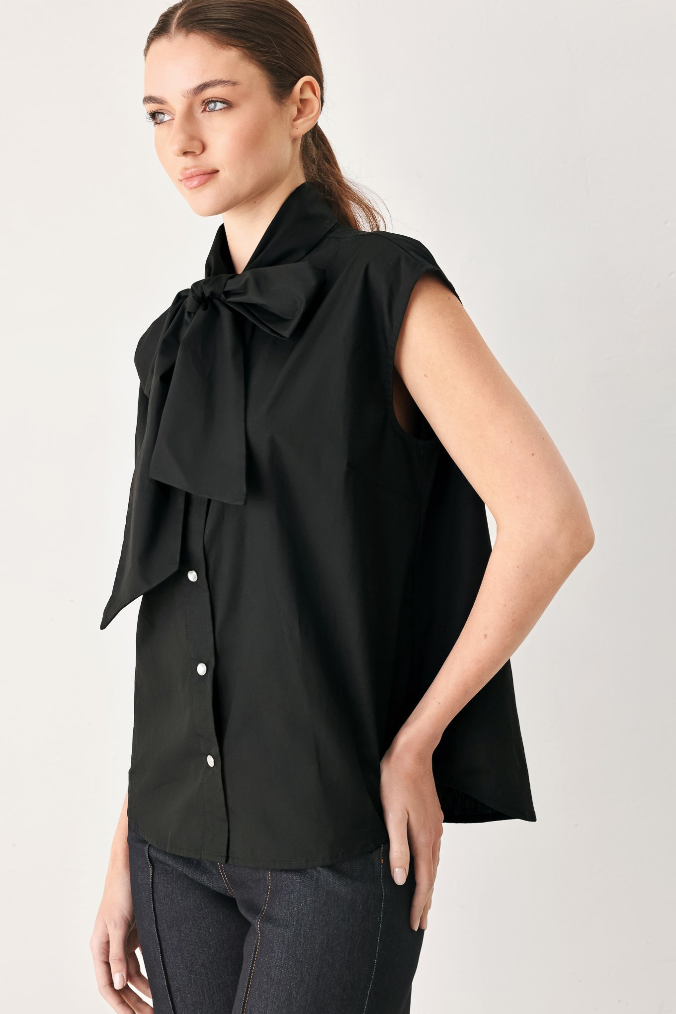Woman wearing a black woven top with front bow tie and button down | FREEMARKET