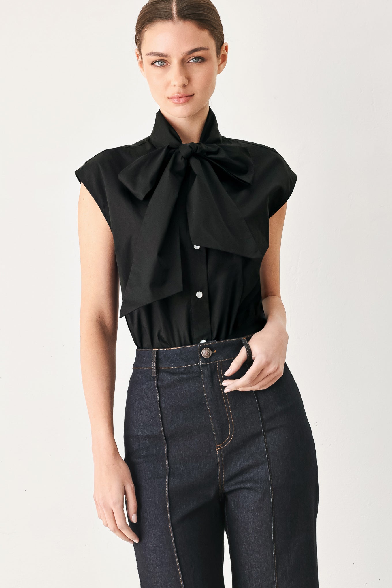 Woman wearing a black woven top with front bow tie and button down | FREEMARKET