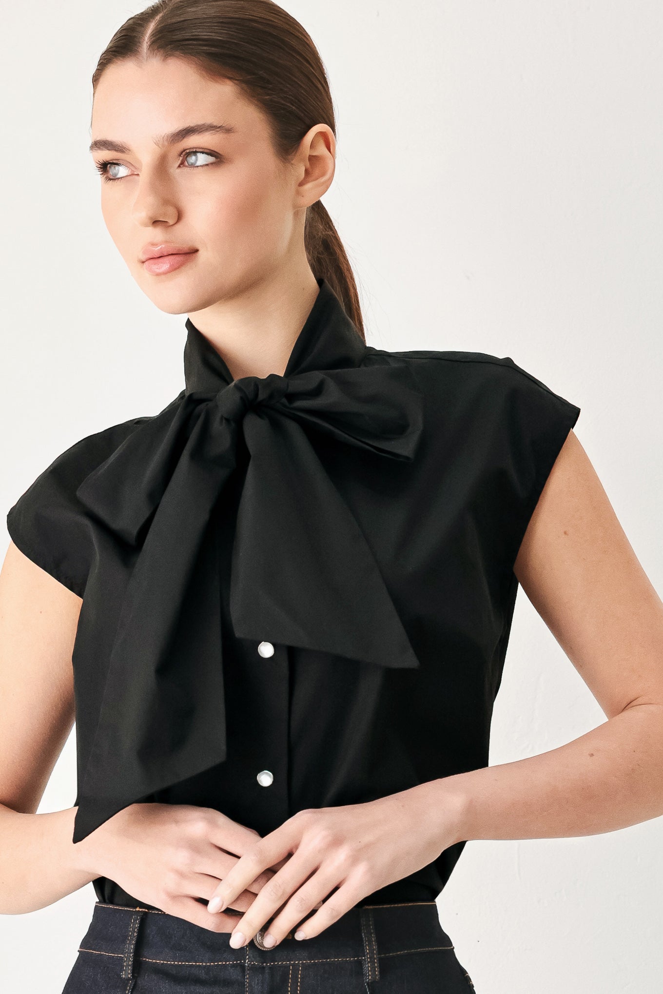 Woman wearing a black woven top with front bow tie and button down | FREEMARKET