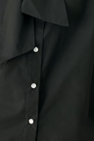Woman wearing a black woven top with front bow tie and button down | FREEMARKET