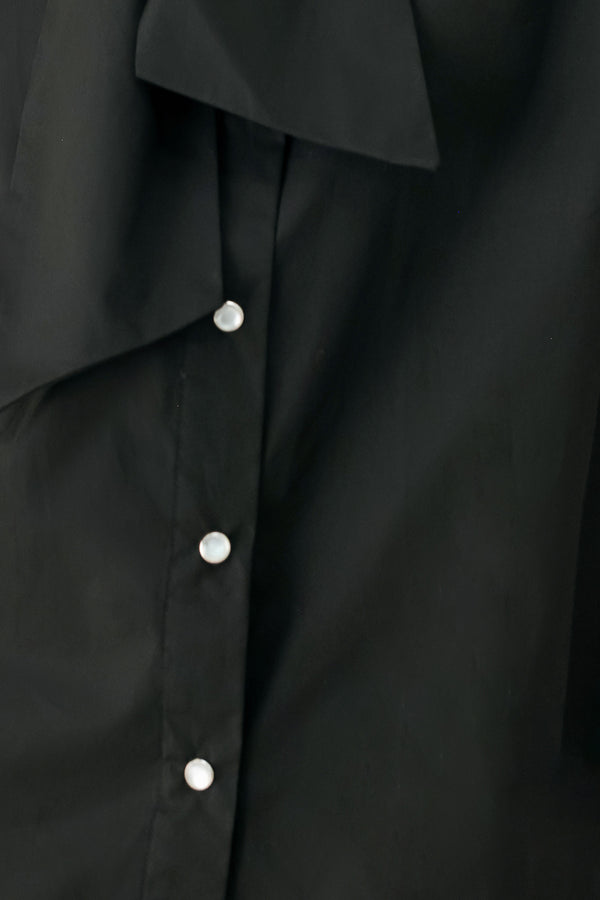 Woman wearing a black woven top with front bow tie and button down | FREEMARKET