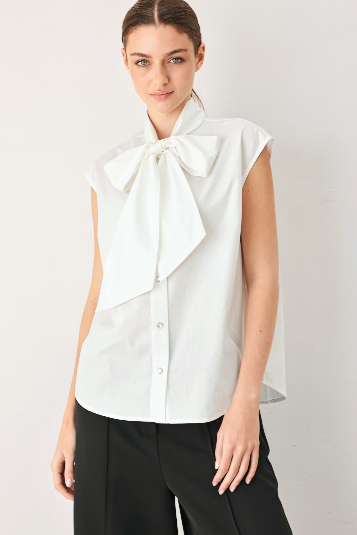 Woman wearing a black woven top with front bow tie and button down | FREEMARKET