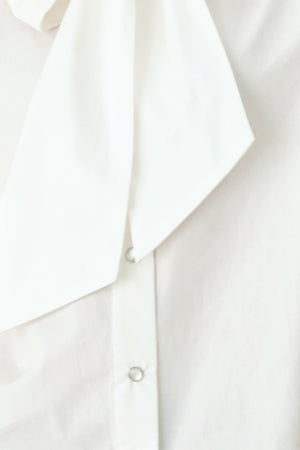 Woman wearing a white woven top with front bow tie and button down | FREEMARKET
