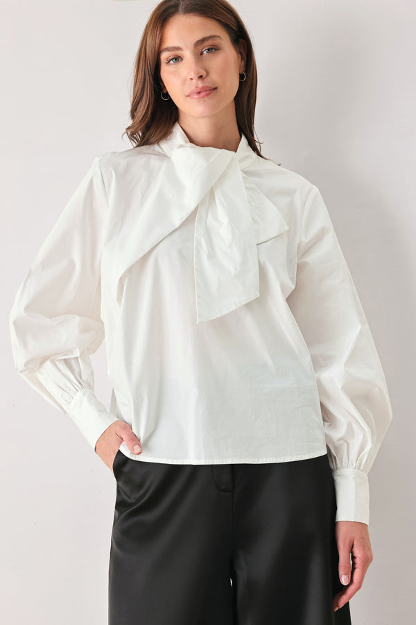 A woman wearing a white long-sleeve blouse with a large draped bow at the collar | FREEMARKET