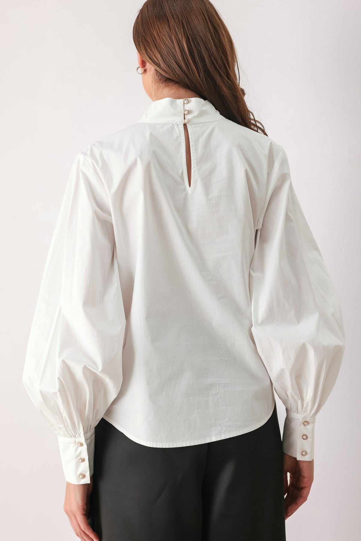 A woman wearing a white long-sleeve blouse with a large draped bow at the collar | FREEMARKET