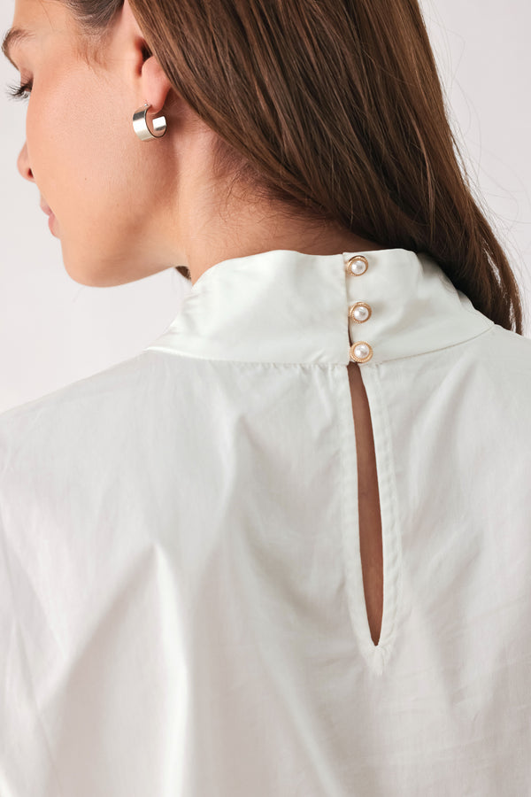 A woman wearing a white long-sleeve blouse with a large draped bow at the collar | FREEMARKET