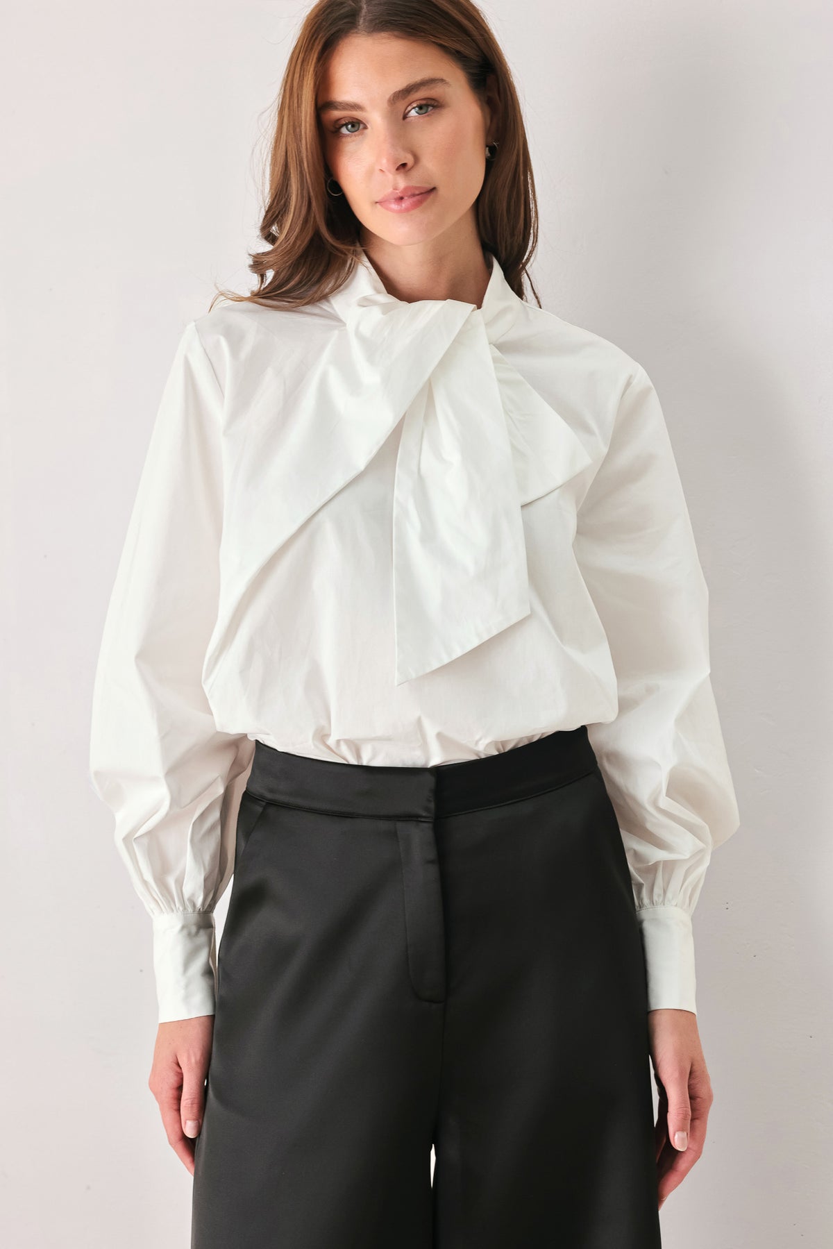 A woman wearing a white long-sleeve blouse with a large draped bow at the collar | FREEMARKET