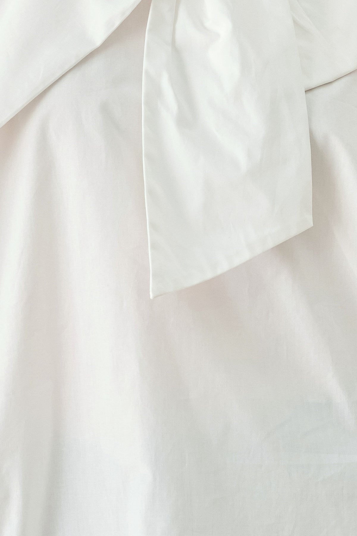 A woman wearing a white long-sleeve blouse with a large draped bow at the collar | FREEMARKET