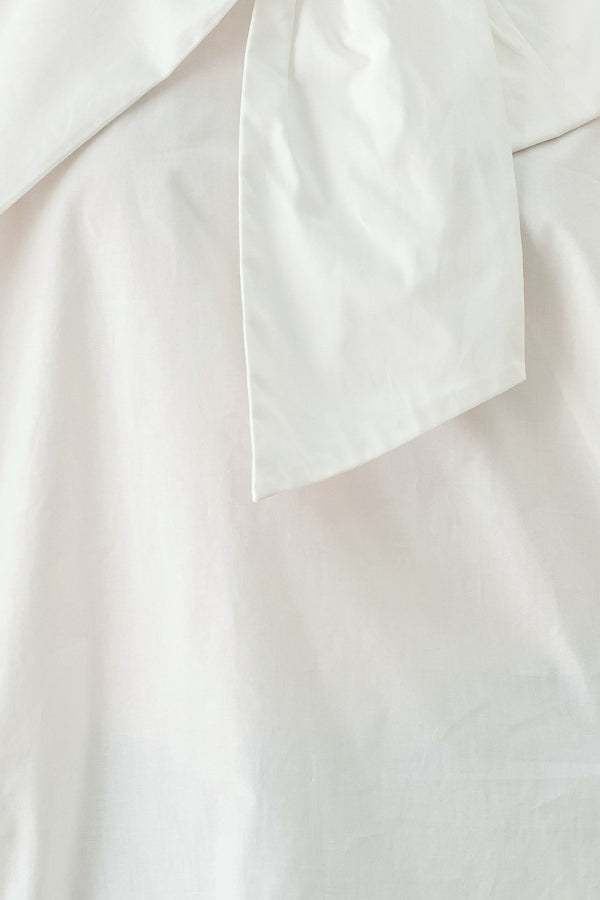 A woman wearing a white long-sleeve blouse with a large draped bow at the collar | FREEMARKET