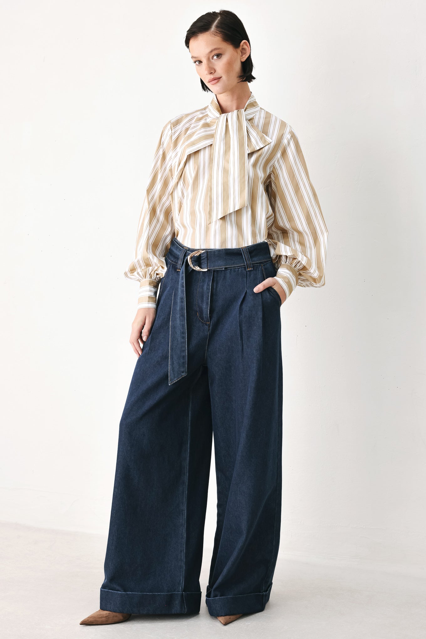 A model wearing a khaki beige and white vertically striped blouse with a large ruffled bow at the collar and voluminous long sleeves | FREEMARKET