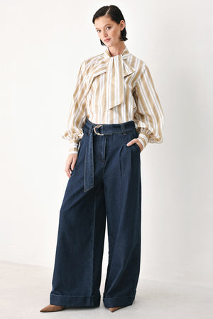 A model wearing a khaki beige and white vertically striped blouse with a large ruffled bow at the collar and voluminous long sleeves | FREEMARKET
