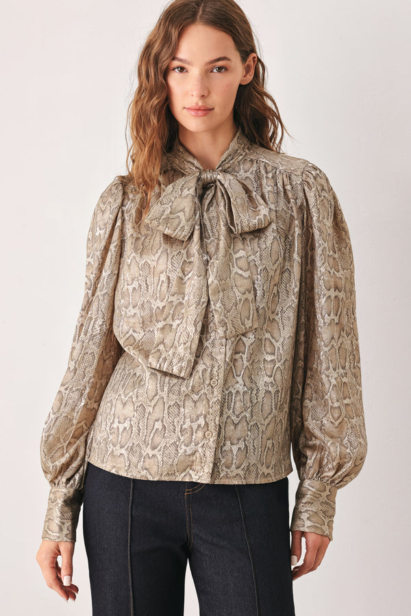 A woman modeling a long-sleeve brown and gold snake-patterned blouse with a tie-neck detail | FREEMARKET