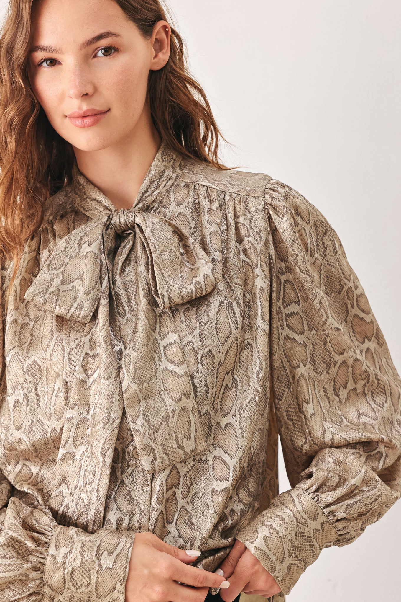 A woman modeling a long-sleeve brown and gold snake-patterned blouse with a tie-neck detail | FREEMARKET