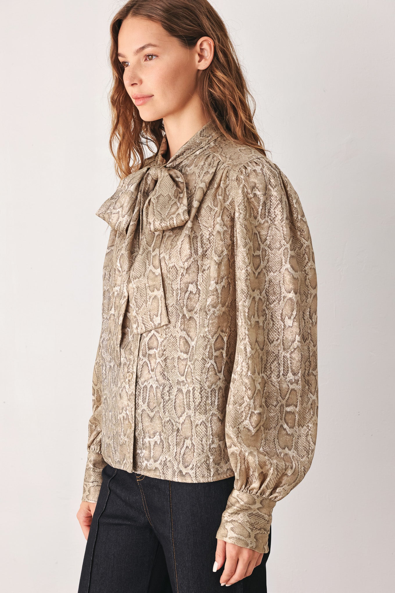 A woman modeling a long-sleeve brown and gold snake-patterned blouse with a tie-neck detail | FREEMARKET