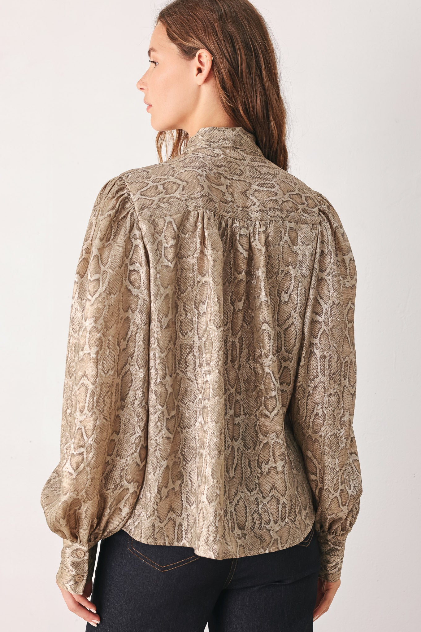 A woman modeling a long-sleeve brown and gold snake-patterned blouse with a tie-neck detail | FREEMARKET