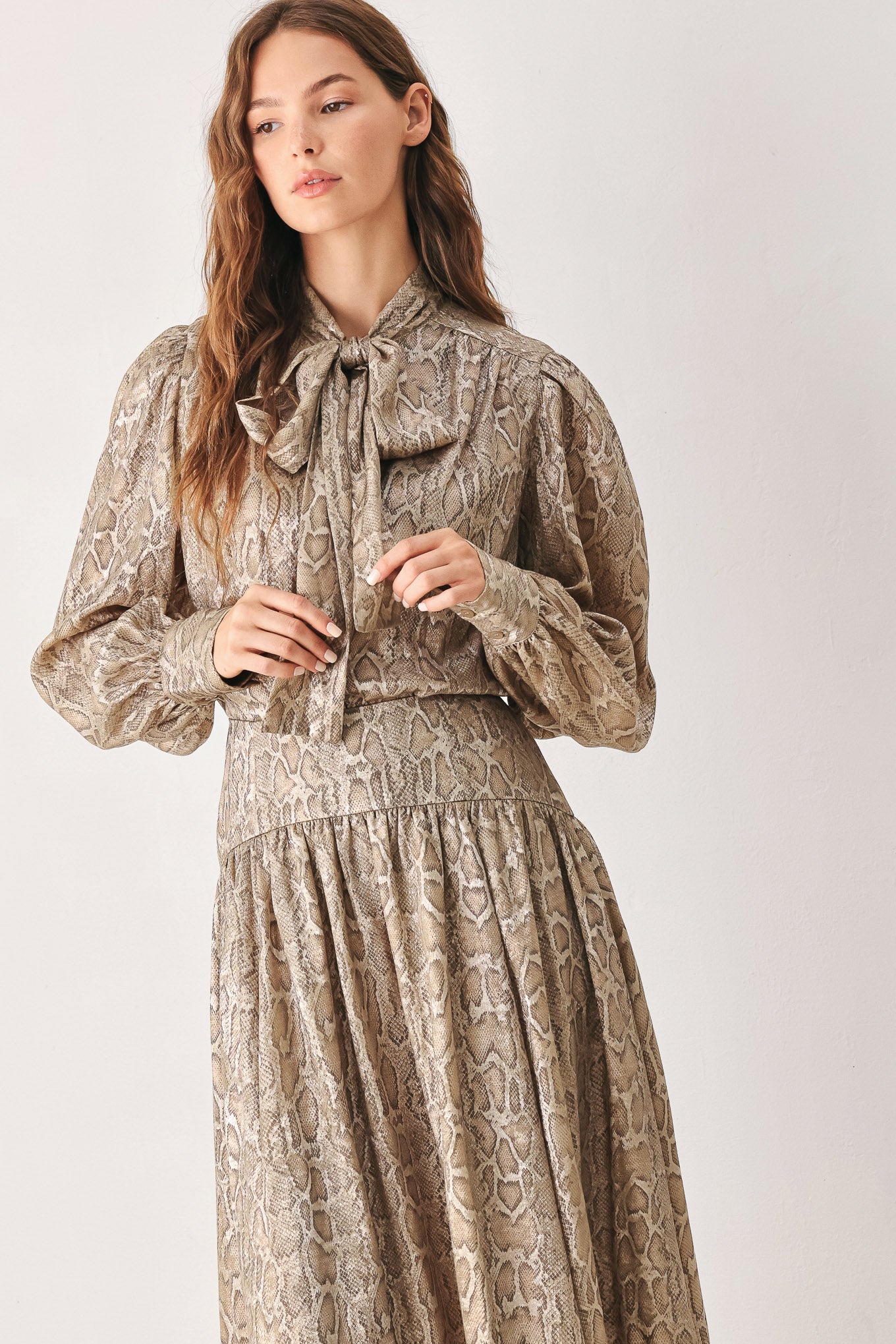 A woman modeling a long-sleeve brown and gold snake-patterned blouse with a tie-neck detail | FREEMARKET